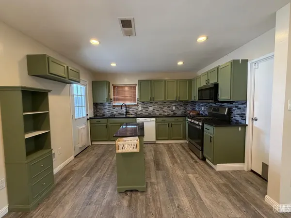 a kitchen with stainless steel appliances granite countertop a refrigerator a stove top oven a sink dishwasher and cabinets with wooden floor