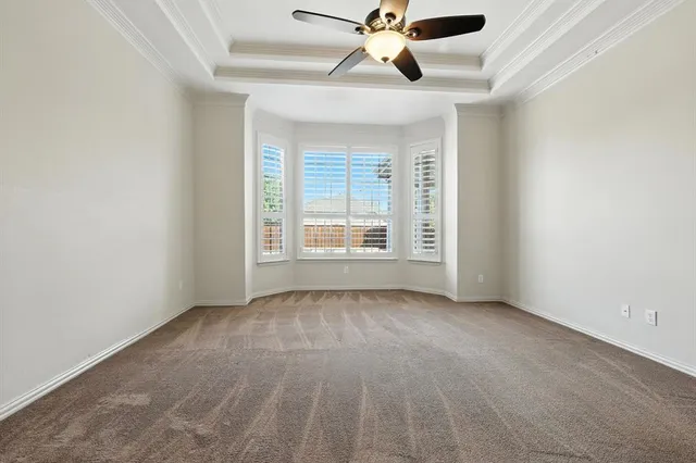 an empty room with chandelier fan and windows