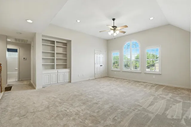 an empty room with windows and ceiling fan