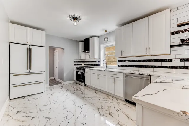 a kitchen with granite countertop a refrigerator sink stove and cabinets