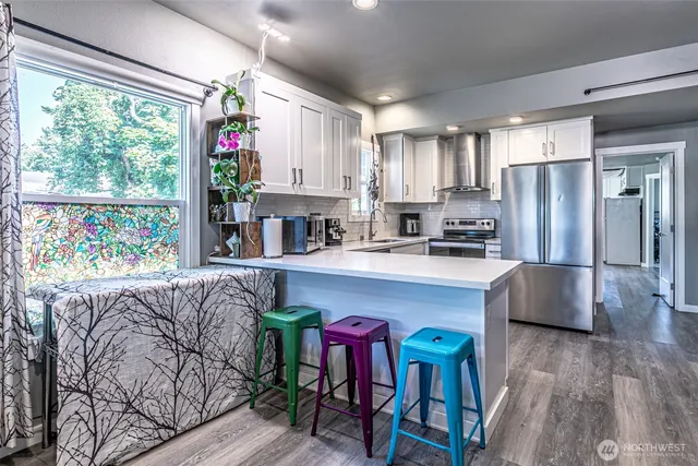 a kitchen with stainless steel appliances granite countertop a refrigerator a stove a sink dishwasher and white cabinets with wooden floor