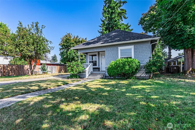 a house that has a big yard with plants and large trees