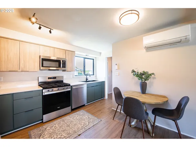 a kitchen with stainless steel appliances granite countertop a sink dishwasher a stove a refrigerator with a dining table and chairs