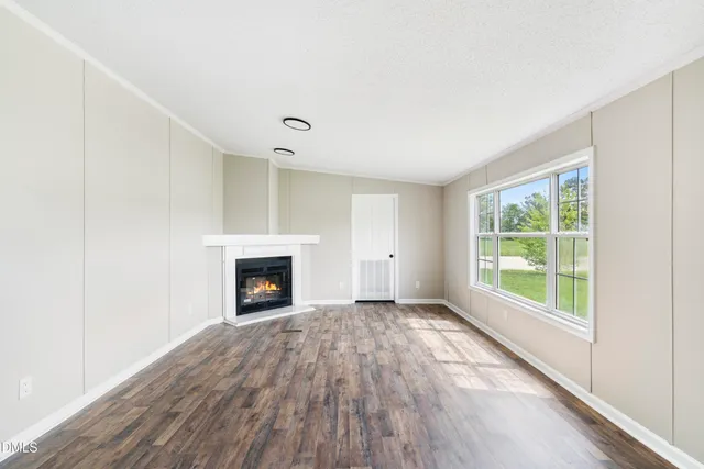 a view of an empty room with window and fire place