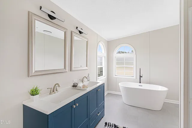 a bathroom with a double vanity sink mirror and bathtub