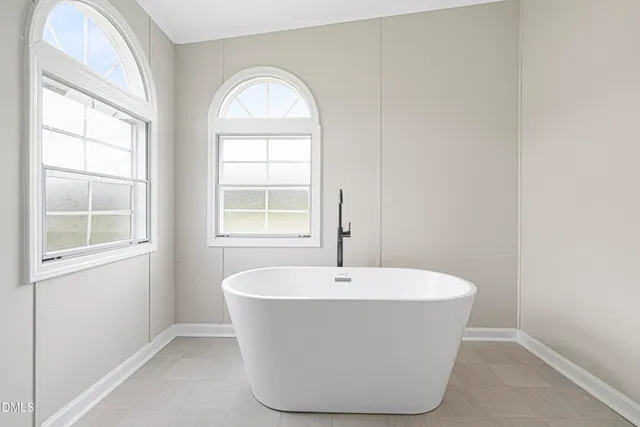 a white bath tub sitting in a bathroom next to a window