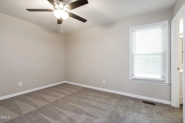 an empty room with a window and a fan