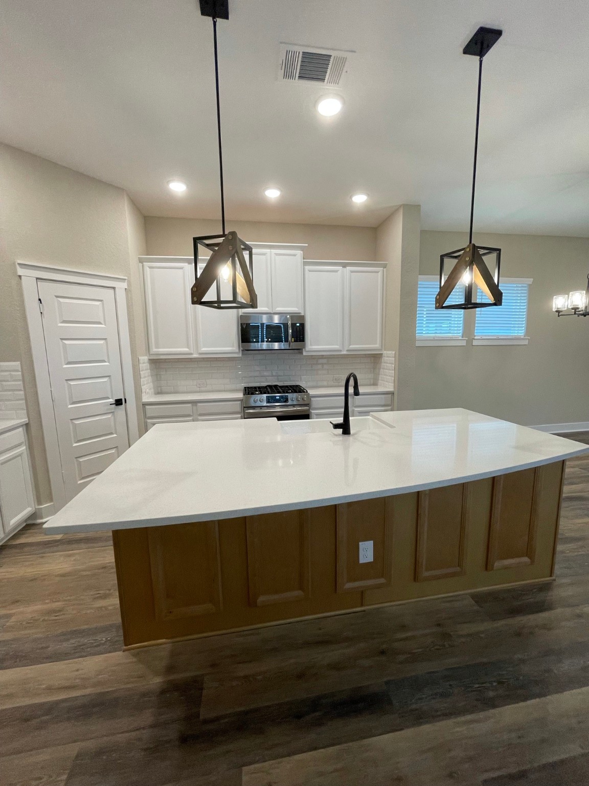 18607 Courteous Way Cypress, TX 77433 - Photo 12 of 37 a kitchen with kitchen island stainless steel appliances a dining table chairs sink and white cabinets