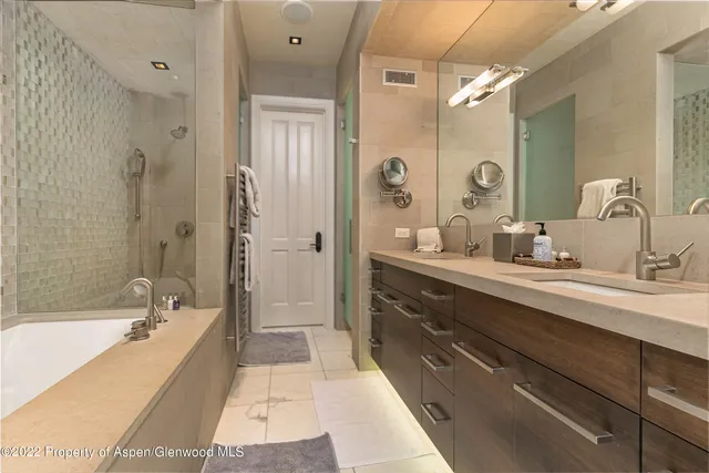 a spacious bathroom with a bathtub double sink shower and mirror