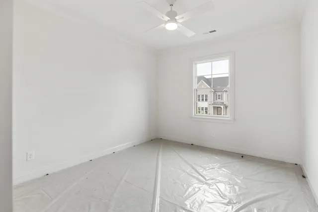 an empty room with windows and fan