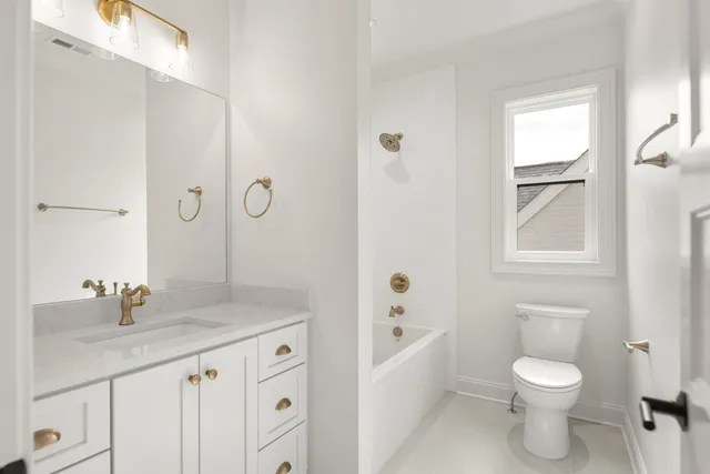 a bathroom with a granite countertop toilet a sink a mirror a bathtub and vanity