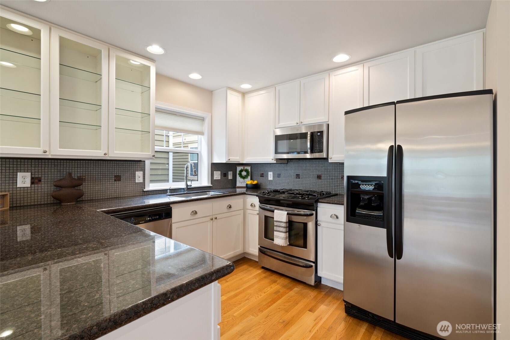 1512 Northwest 57th Street, Unit B Seattle, WA 98107 - Photo 5 of 27 a kitchen with stainless steel appliances granite countertop a refrigerator a stove a sink and a microwave