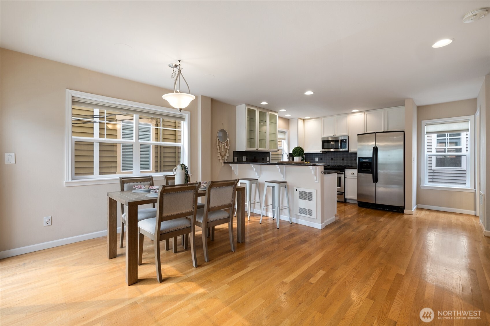 1512 Northwest 57th Street, Unit B Seattle, WA 98107 - Photo 6 of 27 a kitchen with stainless steel appliances kitchen island granite countertop a stove top oven a sink dishwasher a dining table and chairs with wooden floor
