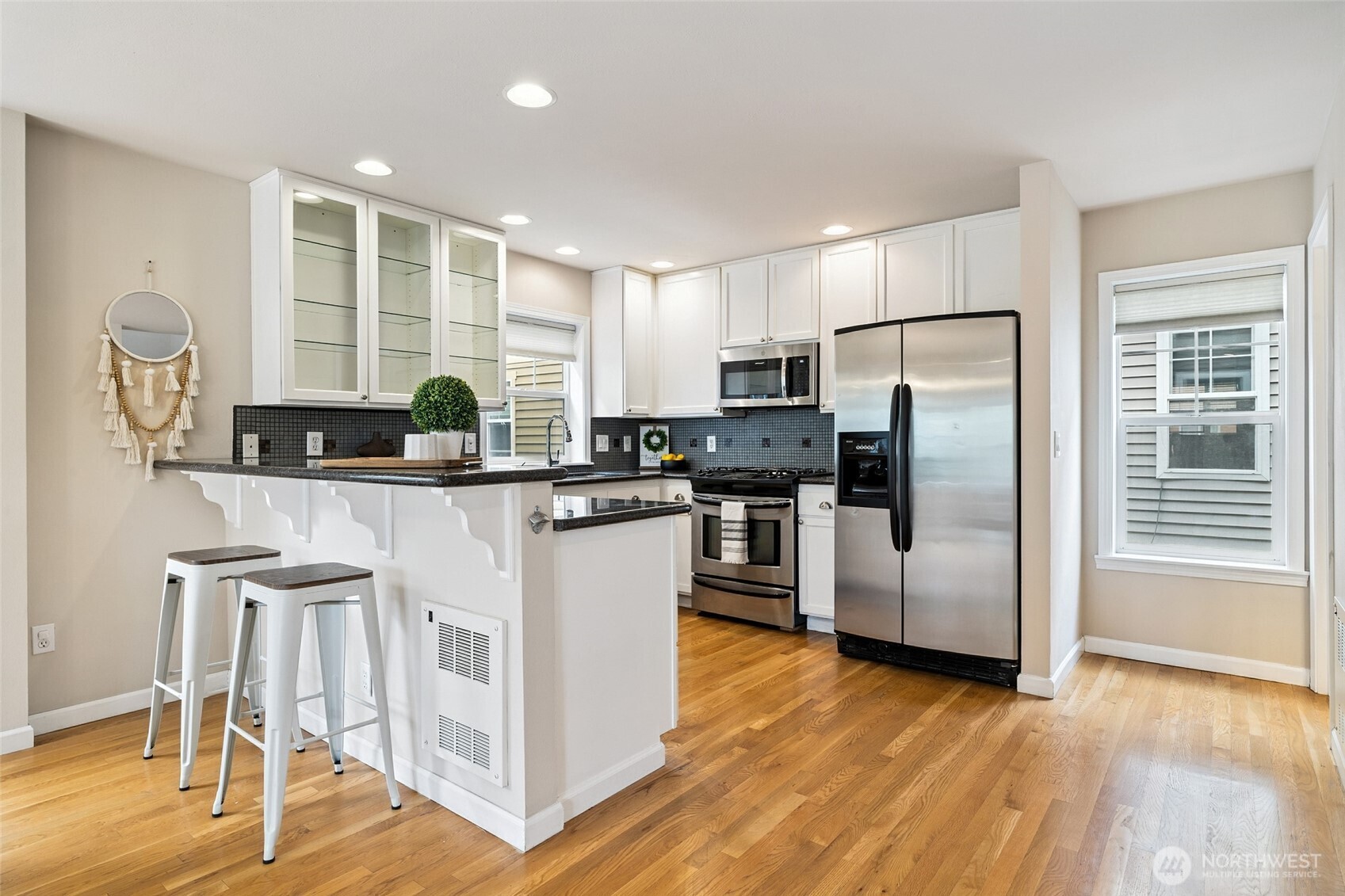 1512 Northwest 57th Street, Unit B Seattle, WA 98107 - Photo 9 of 27 a kitchen with stainless steel appliances granite countertop a refrigerator a stove a sink and white cabinets with wooden floor