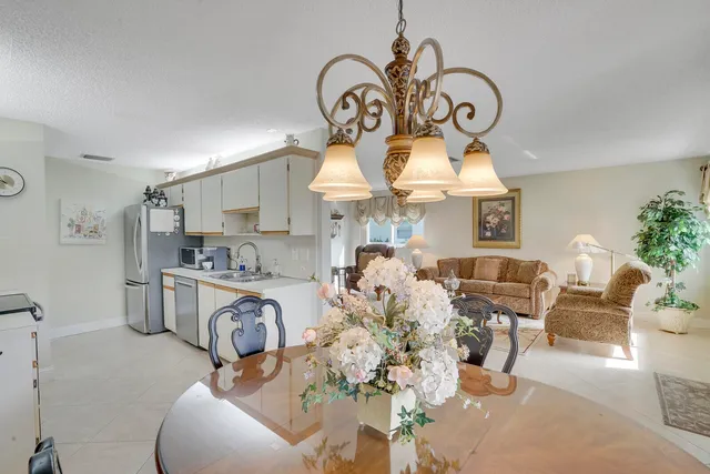 a very nice looking open kitchen with stainless steel appliances kitchen island granite countertop a stove a sink a dining table and chairs