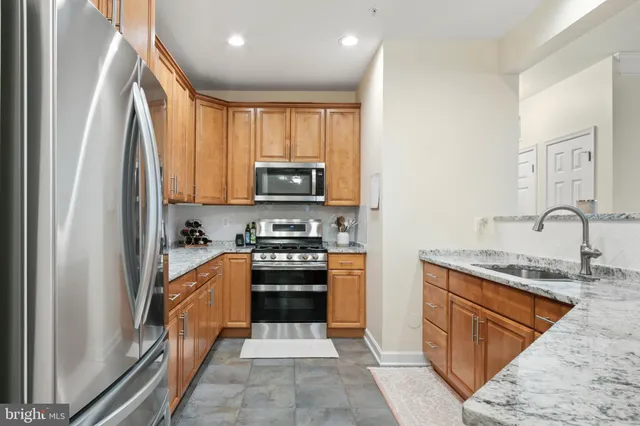 a kitchen with stainless steel appliances granite countertop a sink stove and refrigerator