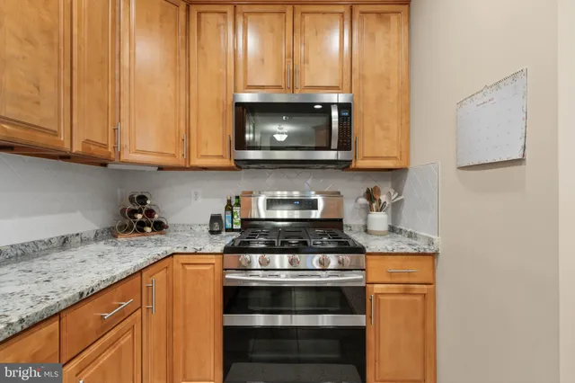 a kitchen with granite countertop a stove a sink and a microwave