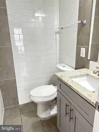 a bathroom with a granite countertop toilet a sink and a mirror