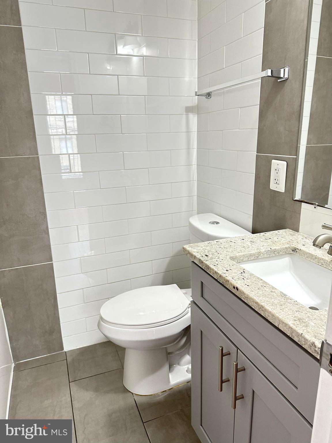 1626 R Street Southeast, Unit 1 Washington, DC 20020 - Photo 13 of 17 a bathroom with a granite countertop toilet a sink and a mirror