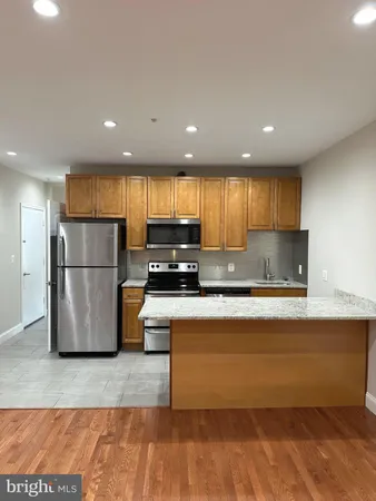 a kitchen with stainless steel appliances granite countertop a refrigerator a stove a sink and a microwave