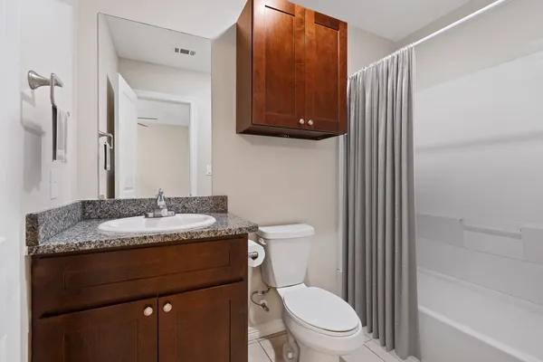 a bathroom with a granite countertop sink toilet and mirror