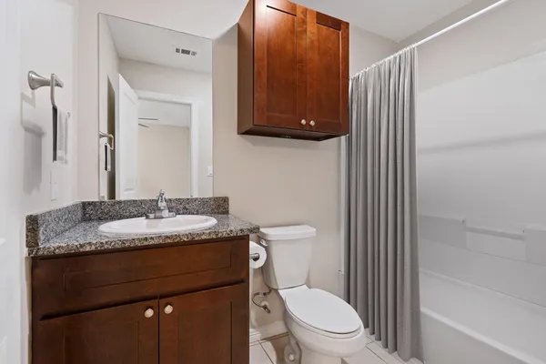 a bathroom with a granite countertop sink toilet and mirror