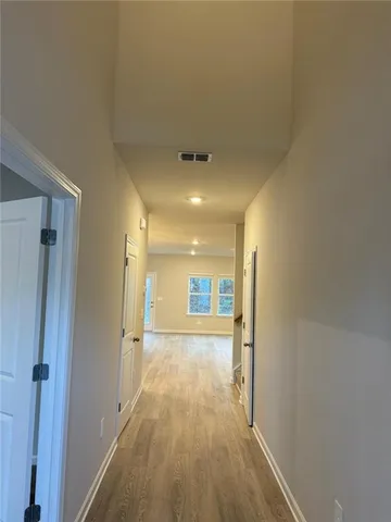 a view of a hallway with wooden floor and a bathroom
