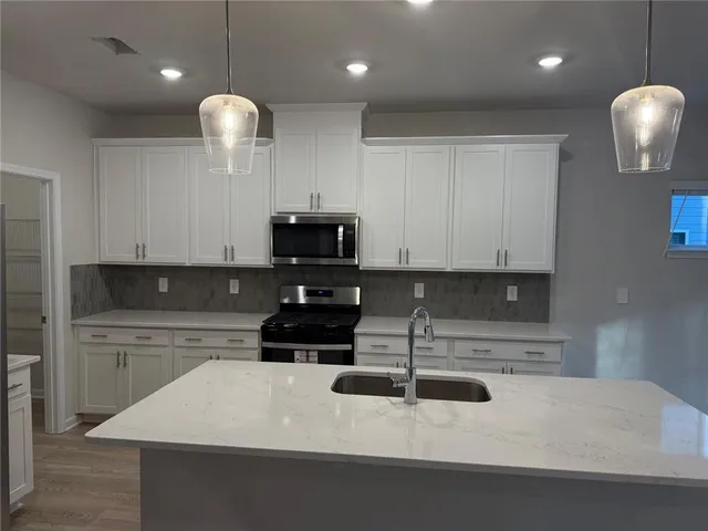 a kitchen with kitchen island a sink stainless steel appliances and cabinets