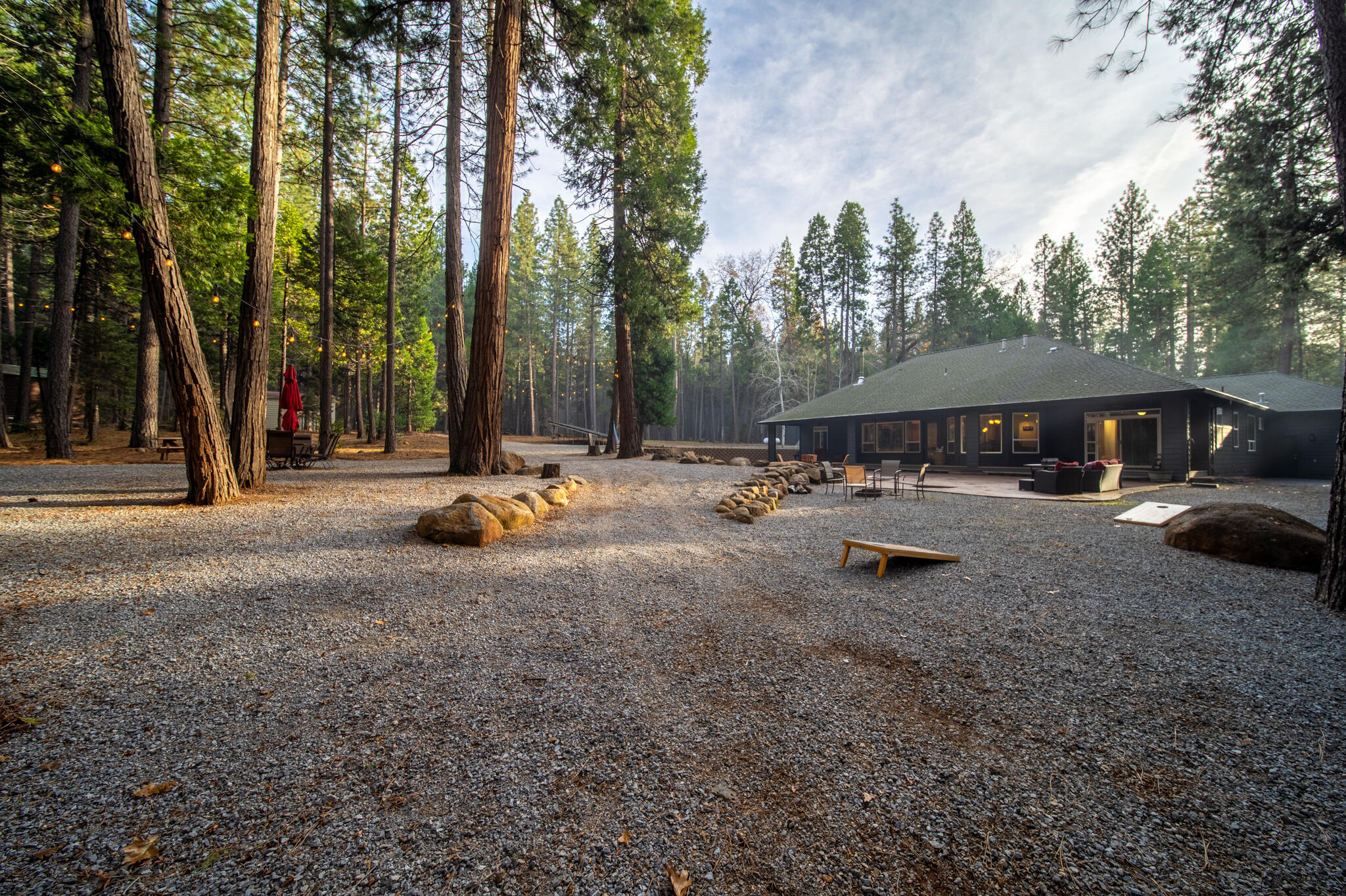 7795 Eastmoore Road Shingletown, CA 96088 - Photo 46 of 61 a backyard of a house with table and chairs under an umbrella