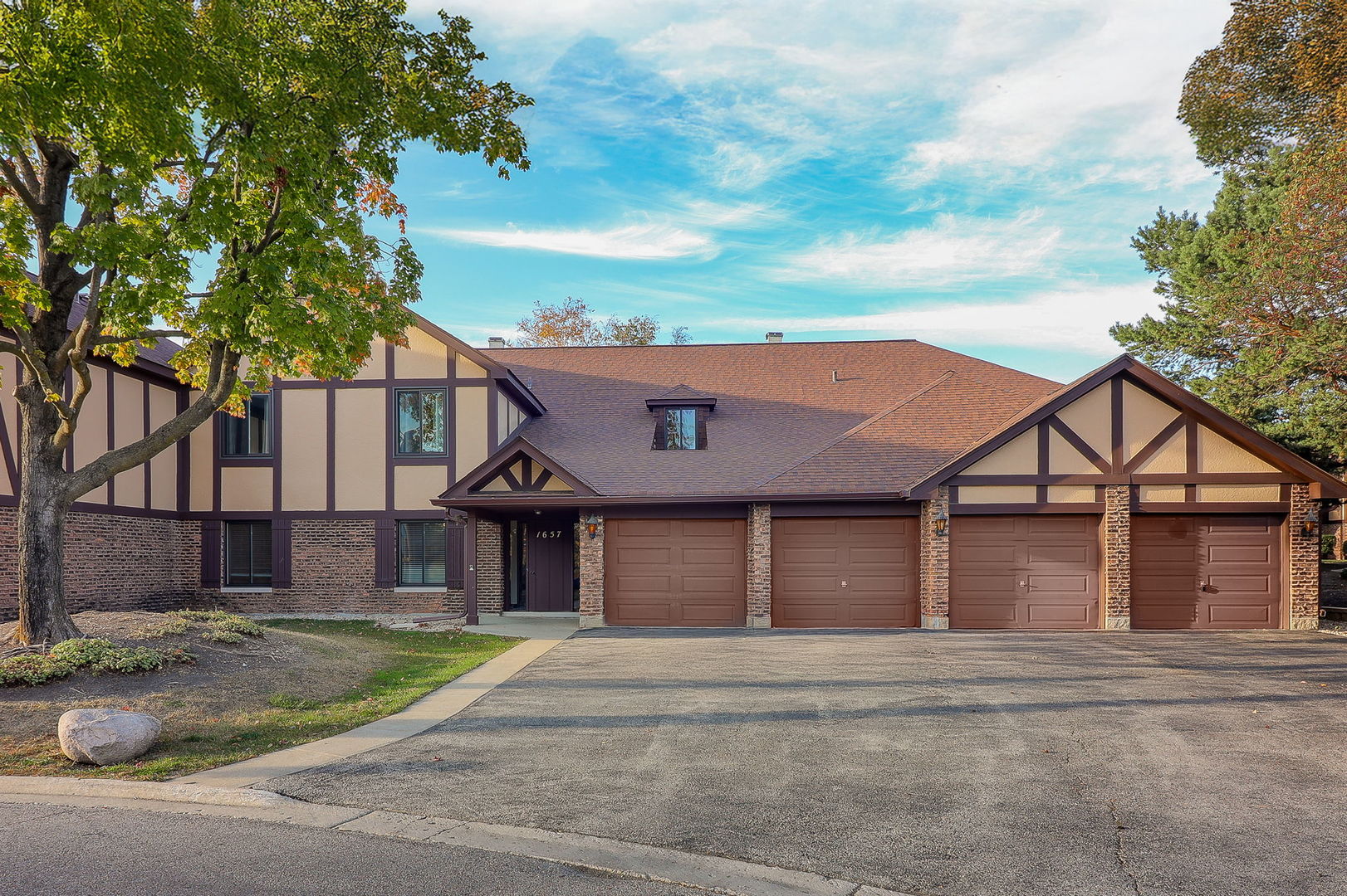 a front view of a house with a garden and trees