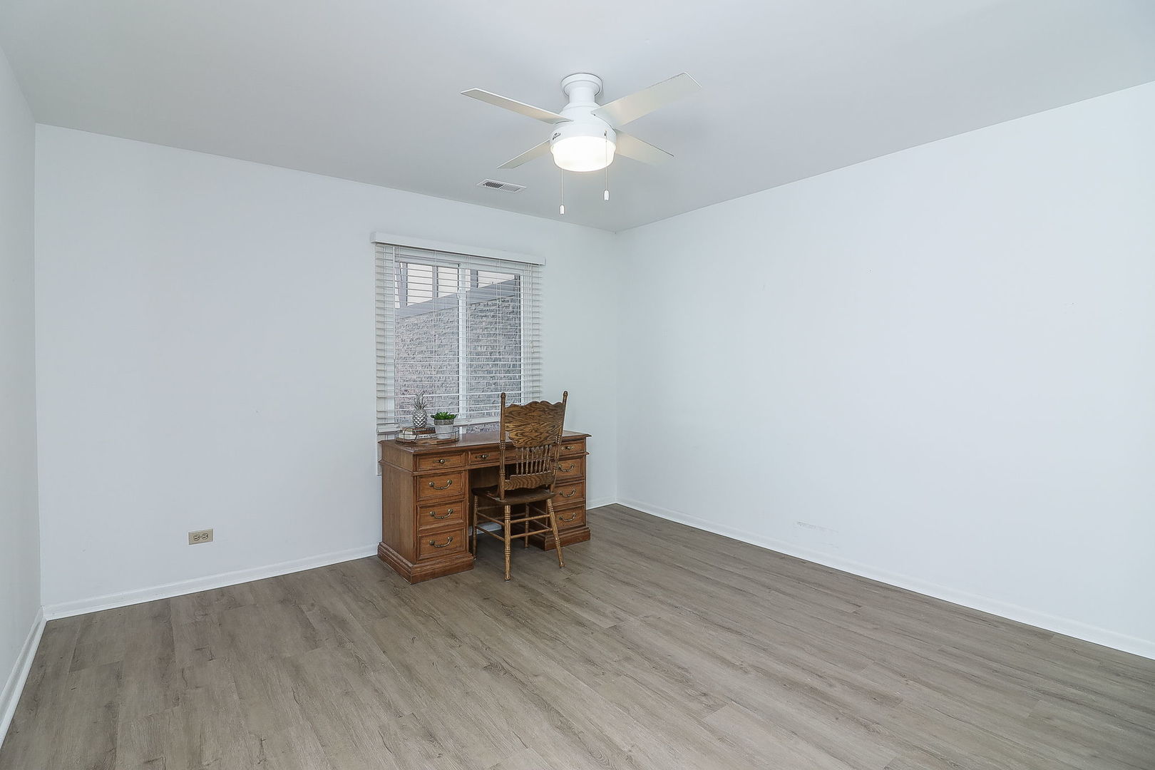 1657 Dover Court, Unit D Wheaton, IL 60189 - Photo 10 of 15 an empty room with wooden floor and a ceiling fan