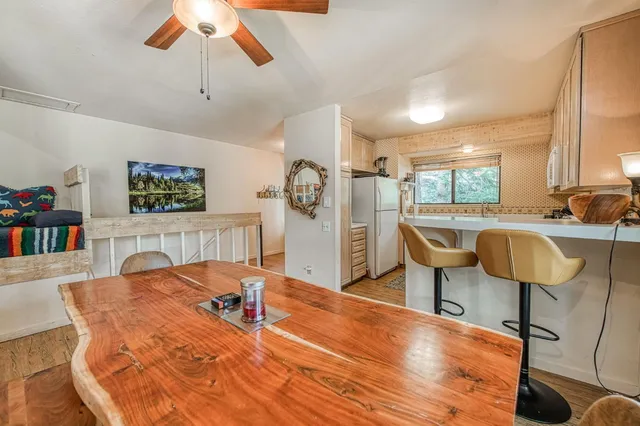 a living room with a table chairs and a dining table with bookshelf