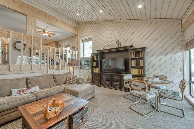 a living room with furniture a flat screen tv and a table