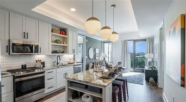 a kitchen with stainless steel appliances granite countertop a stove a sink dishwasher a refrigerator white cabinets and wooden floor