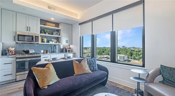 a living room with stainless steel appliances granite countertop a couch and a large window