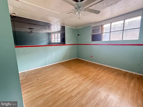 a view of empty room with wooden floor and fan