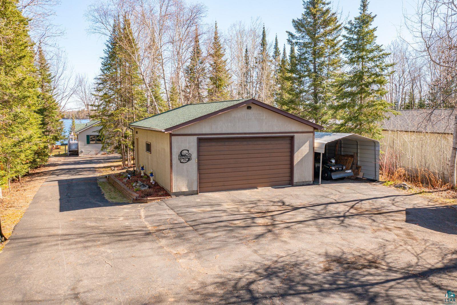 4452 Moccasin Point Road Tower, MN 55790 - Photo 33 of 44 Detached garage building featuring a brown overhead door, a green shingled roof, and an attached carport