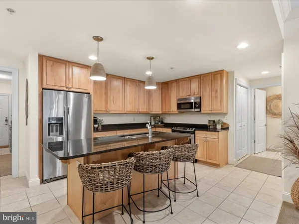 a kitchen with stainless steel appliances granite countertop a stove a sink a dining table and chairs with wooden floor