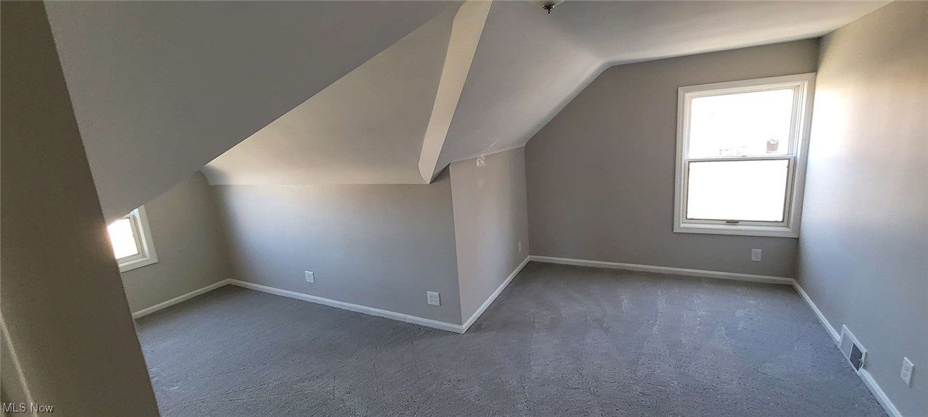 6149 North Canterbury Road Parma, OH 44129 - Photo 12 of 16 Additional living space with lofted ceiling, a healthy amount of sunlight, and dark colored carpet