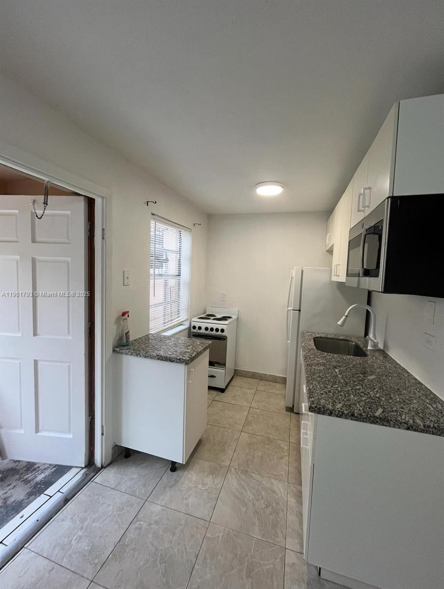 1036 Northwest 3rd Street, Unit 1 Miami, FL 33128 - Photo 11 of 22 a kitchen with stainless steel appliances granite countertop a sink and a refrigerator