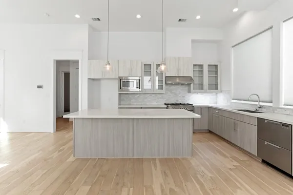 a large kitchen with stainless steel appliances kitchen island a large counter top and a wooden floors