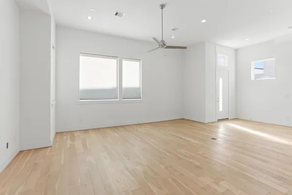 an empty room with wooden floor and windows