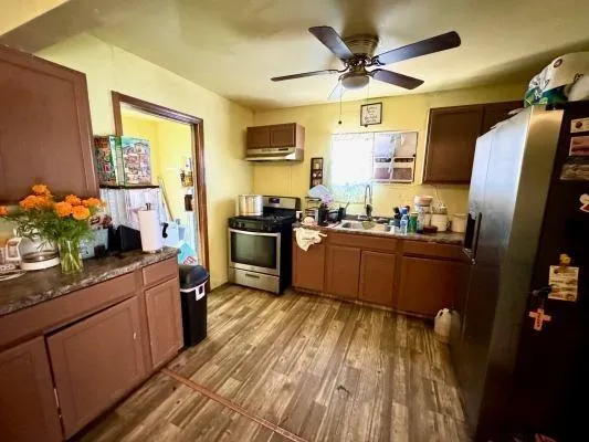 a kitchen with stainless steel appliances a sink a stove a refrigerator cabinets and a dining table