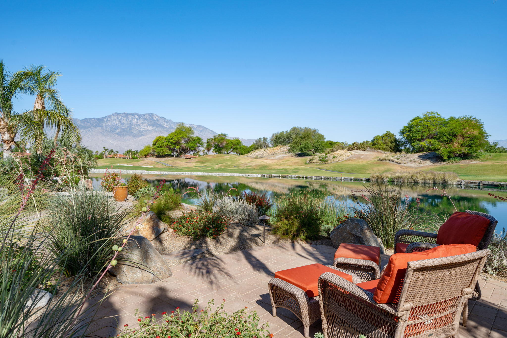 372 Loch Lomond Road Rancho Mirage, CA 92270 - Photo 39 of 51 a view of a lake with couches and table and chairs under an umbrella