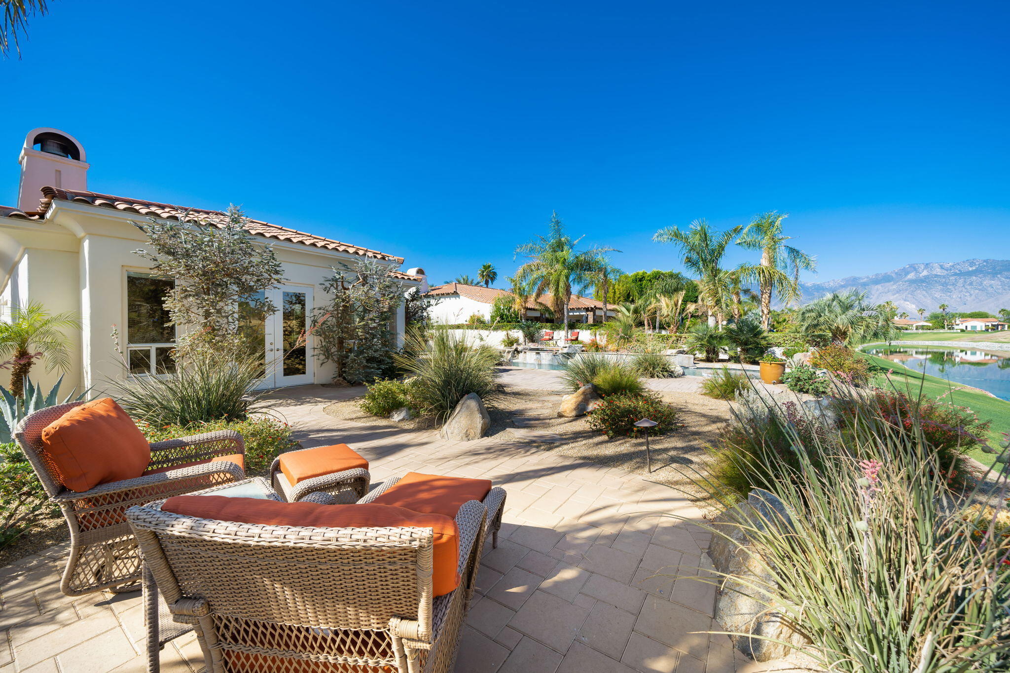 372 Loch Lomond Road Rancho Mirage, CA 92270 - Photo 40 of 51 a view of a patio with couches table and chairs under an umbrella with potted plants