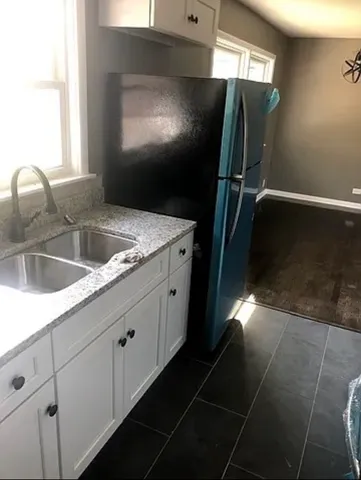 a kitchen with granite countertop a sink and a refrigerator