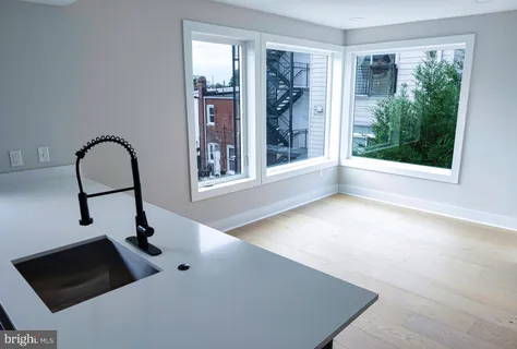 a view of an empty room with windows and kitchen view