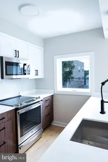 a kitchen with stainless steel appliances a stove a microwave and white cabinets