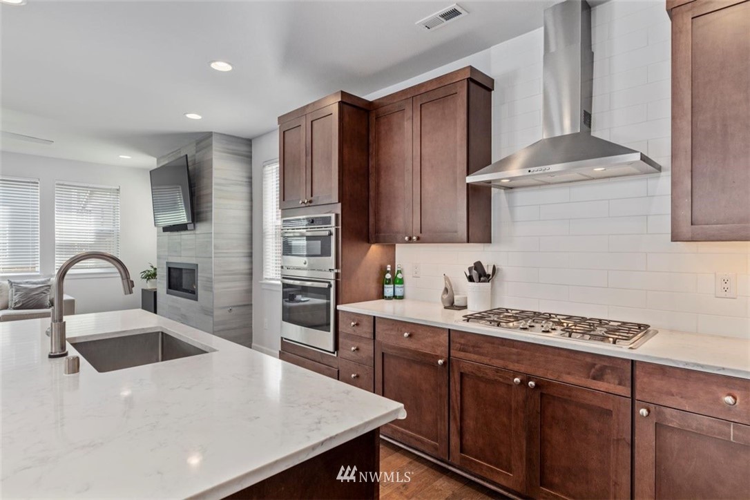 320 181st Street Southeast Bothell, WA 98012 - Photo 10 of 40 a kitchen with stainless steel appliances a sink dishwasher a refrigerator cabinets and wooden floor