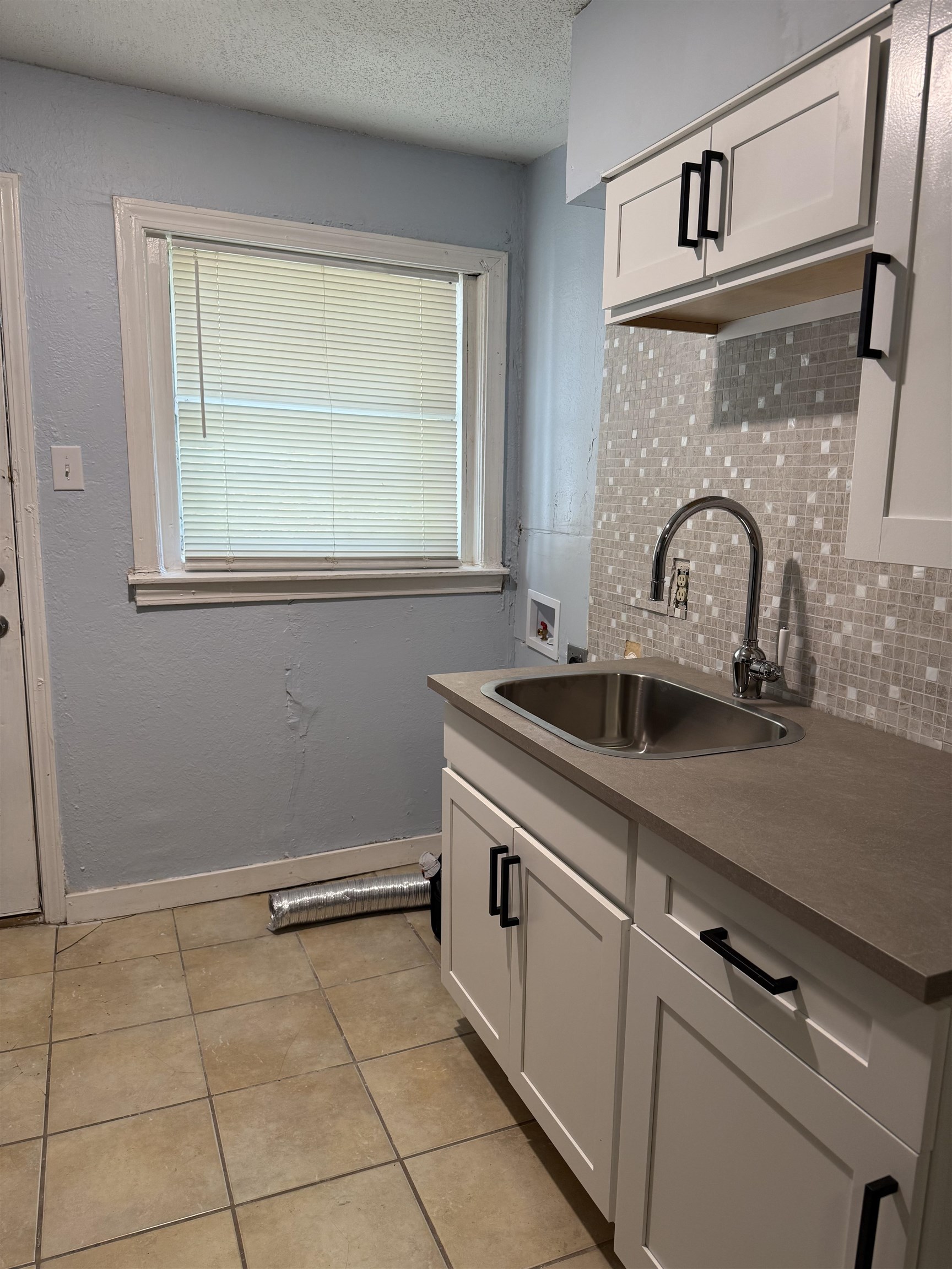 1248 Meda Street Memphis, TN 38114 - Photo 20 of 24 Kitchen featuring a textured ceiling, white cabinetry, backsplash, light tile patterned floors, and dark countertops